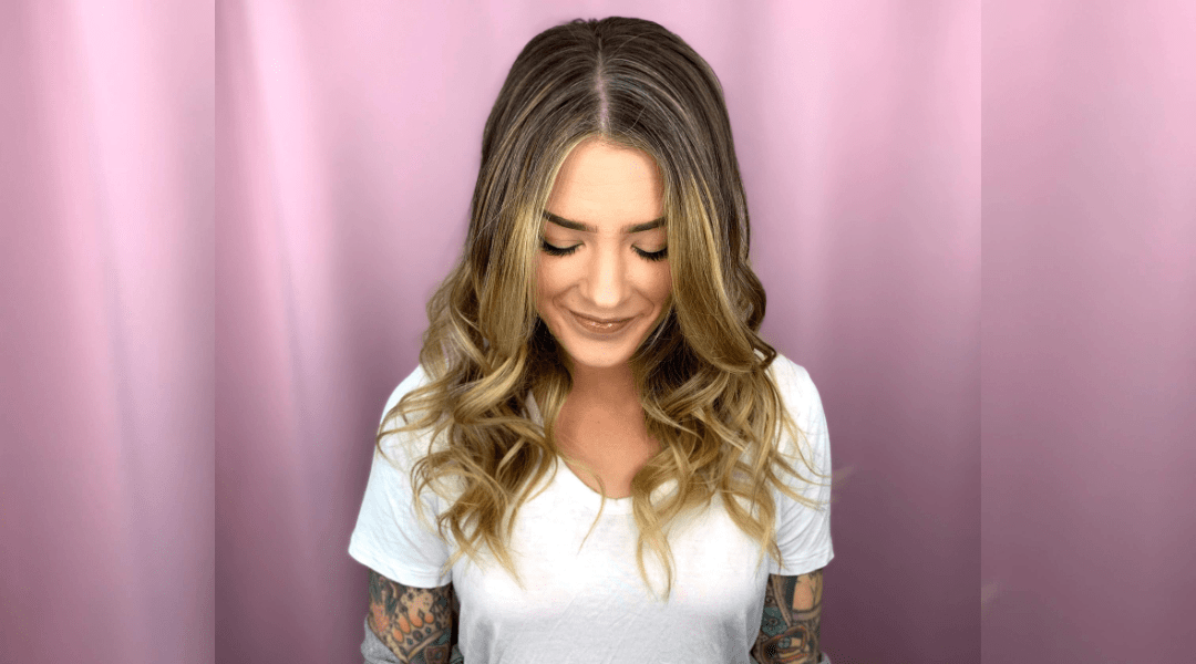 Woman with curly blonde hair showcasing premium balayage highlights.
