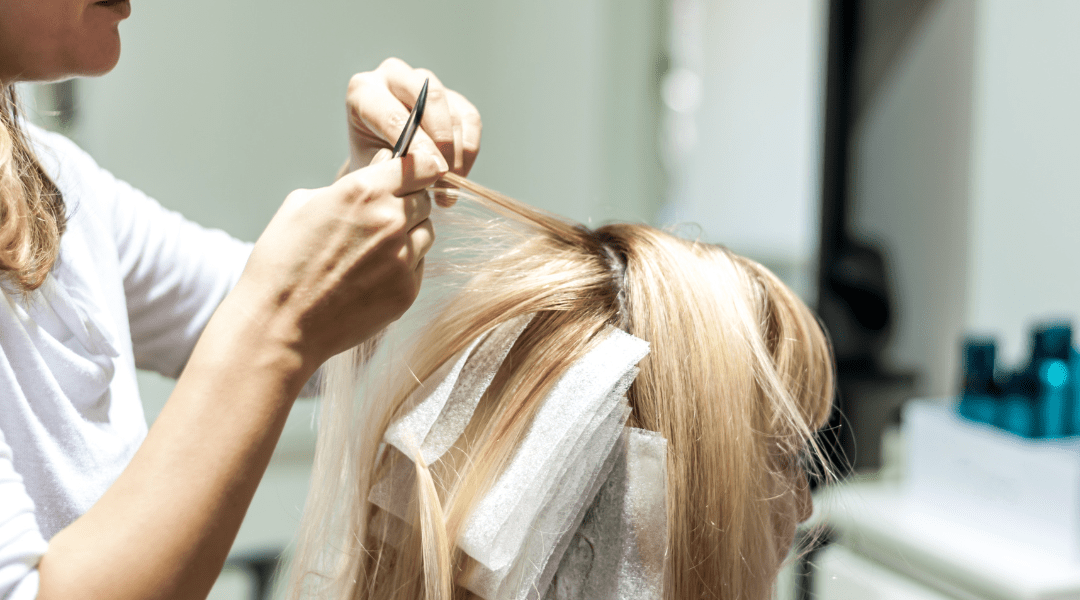 Close-up of a stylist adding foil highlights to enhance the client's hair color.