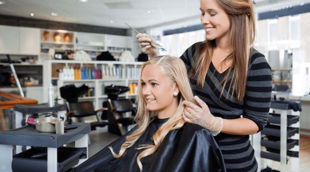 Hairdresser applying single-process color to a client’s hair in a beauty salon.