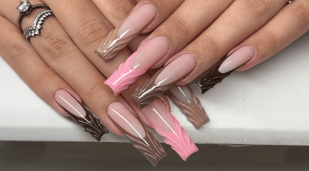 Long clear V-cut nails with nude base, brown gradient tips, and 3D sculpted feather designs accented by silver ring