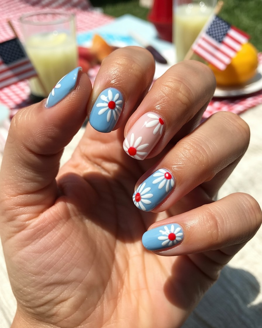 Oval nails with sky-blue base and white daisies with red centers for a festive look.