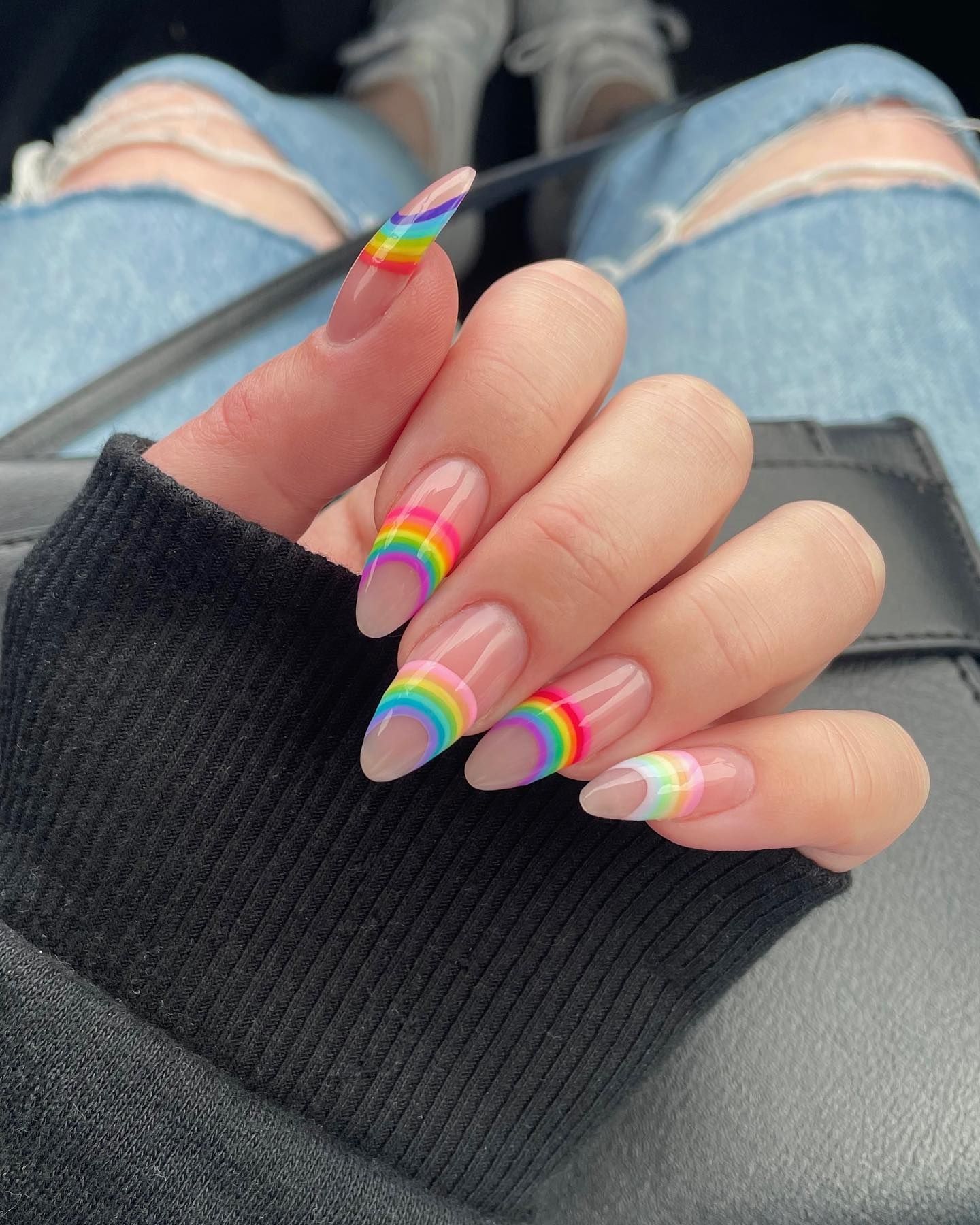 Close-up of Nude + Rainbow Nail Design with a neutral nude base, colorful abstract rainbow accents, and minimalist French tips for a fun yet classy look.