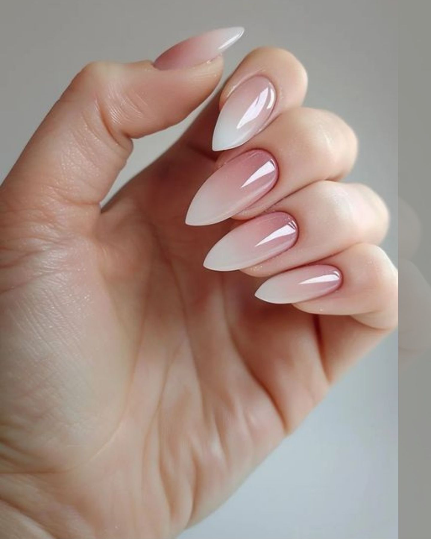 Almond-shaped nails with glossy ombré V-cut design fading from dark pink tips to light white bases