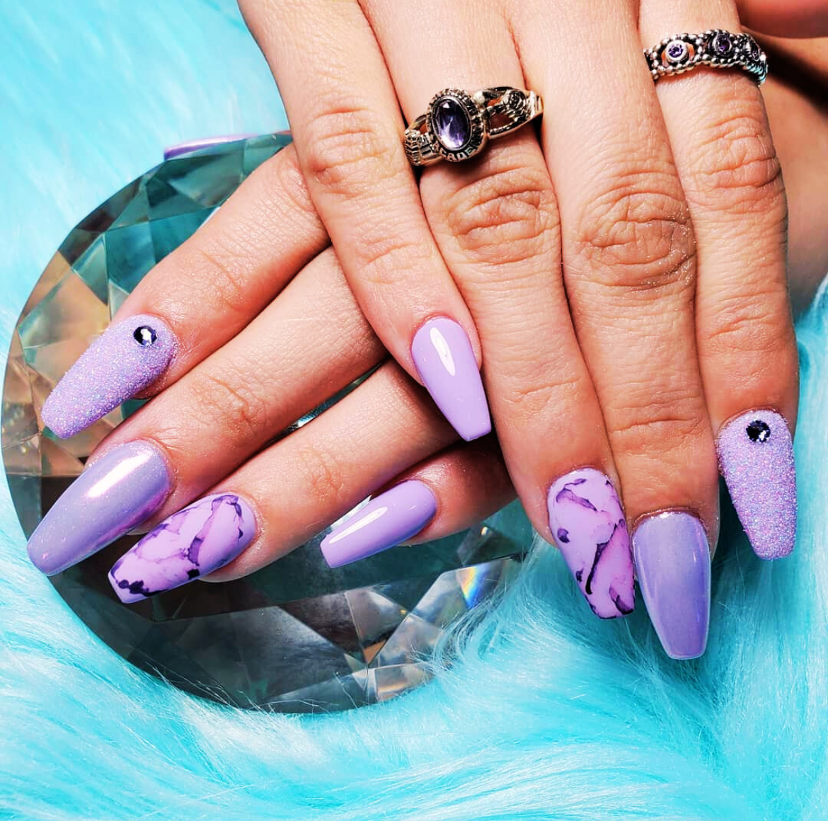 Purple Chrome Nail Design featuring long nails with a mix of solid chrome purple, marble swirls, and glitter accents for a bold, artistic look