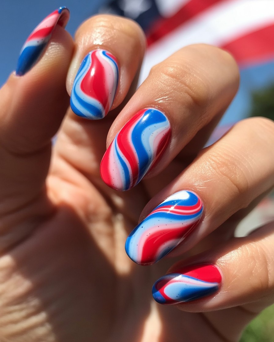 Almond nails with glossy red, white, and blue water-marble tie-dye design.