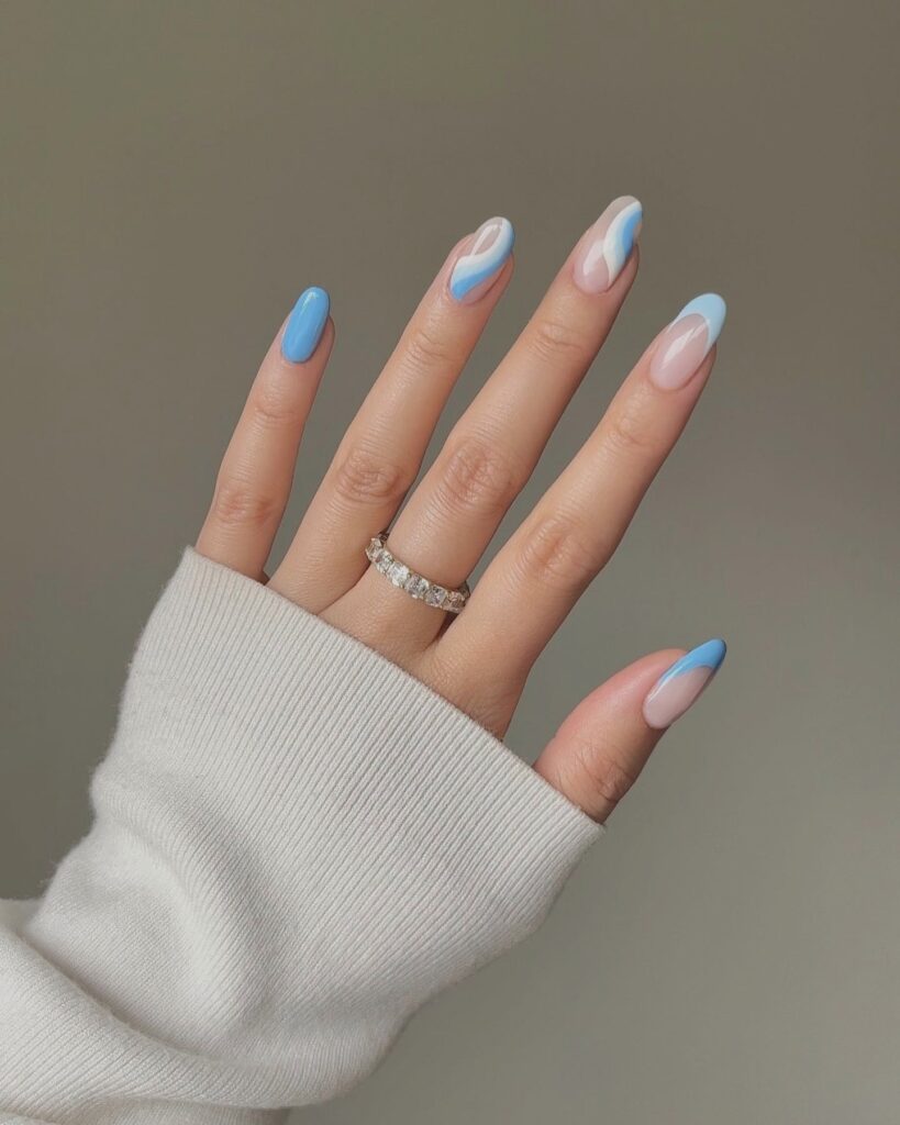 Hand with blue and pink marbled nails, silver eternity ring on ring finger, styled with a soft knit sweater.