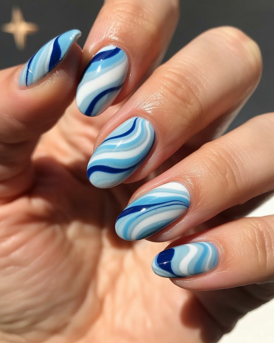 Almond-shaped nails with glossy blue and white marble design inspired by fireworks smoke.