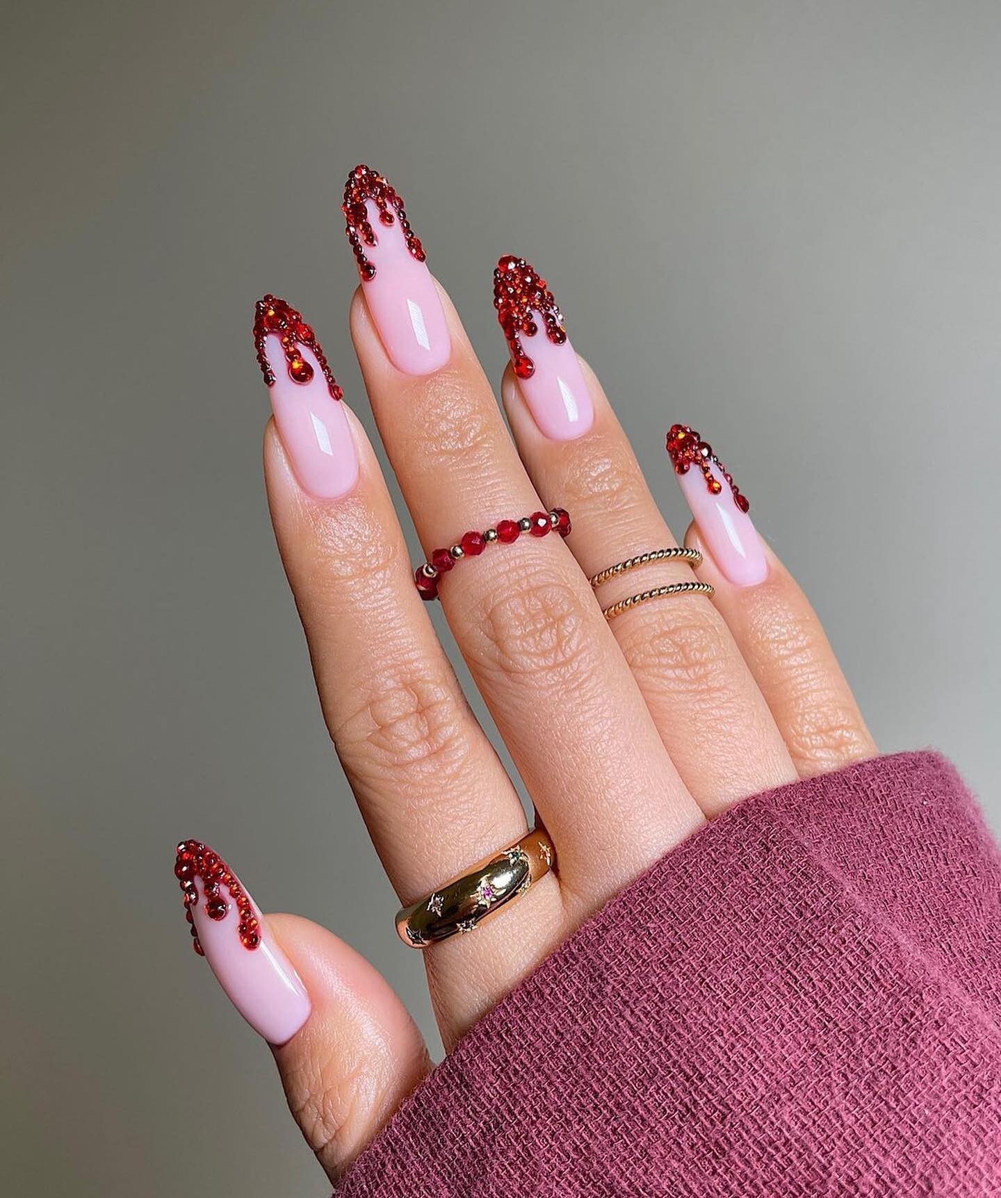hand with relaxed straight fingers showing medium-length glossy deep red nails with subtle, hand-painted blood drip design near tips.