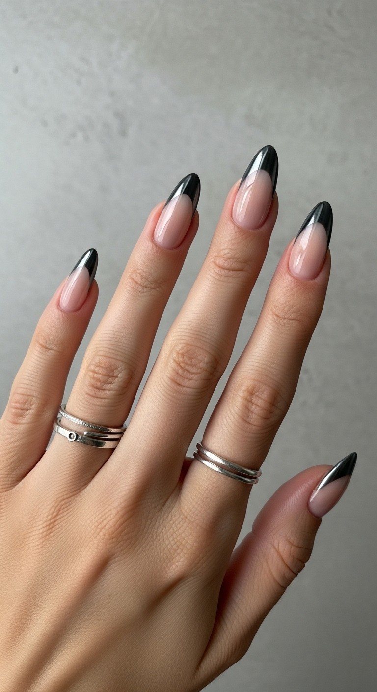 Almond-shaped nails with charcoal chrome French tips on a sheer nude base