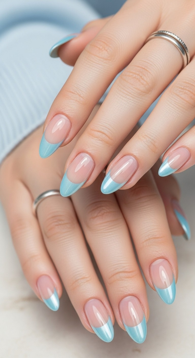 Almond nails with a sheer nude base and shiny light blue chrome French tips on a fully visible, naturally posed hand.