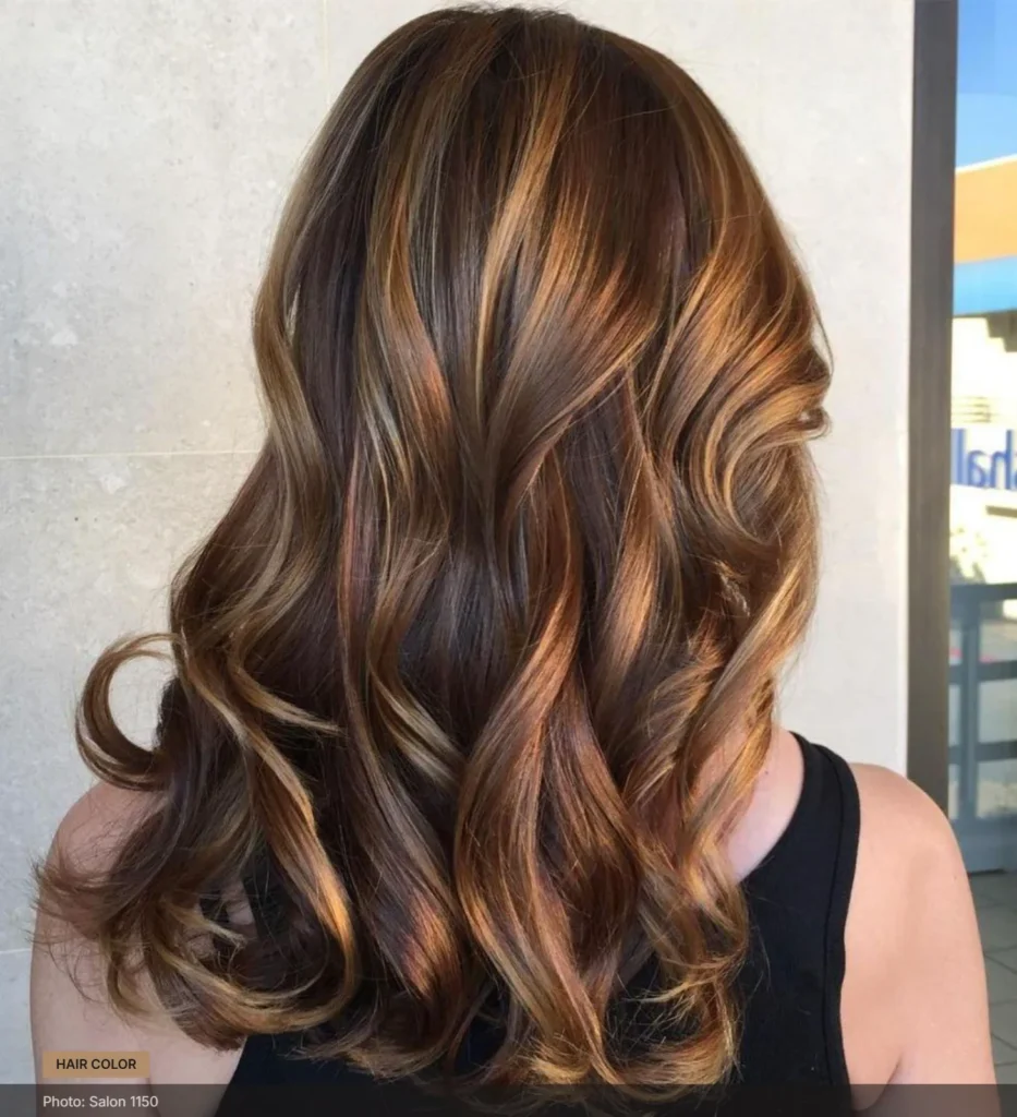 Chestnut brown hair with caramel and honey highlights styled in soft waves