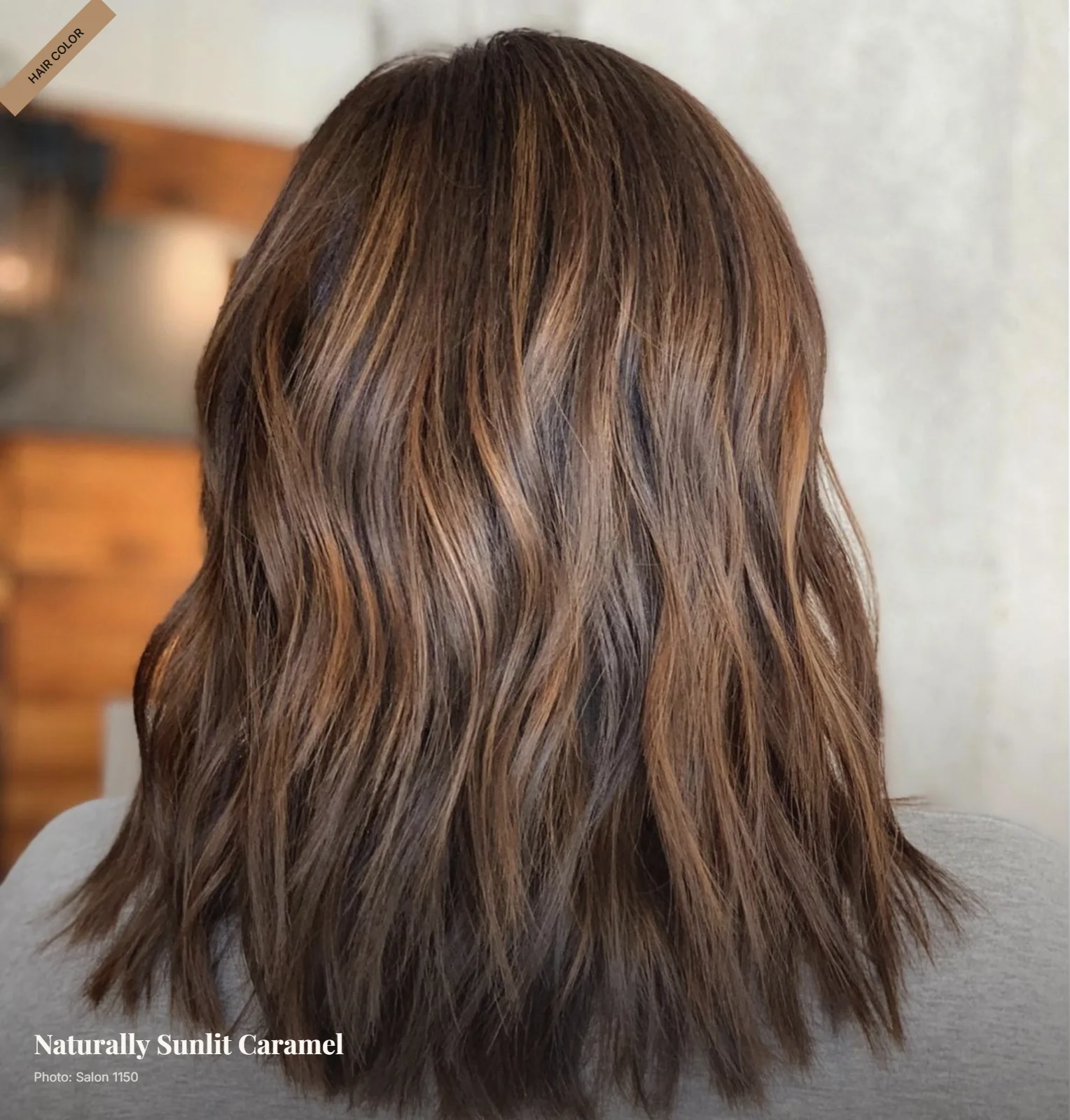 Natural brown hair with soft caramel balayage styled in loose waves under warm light
