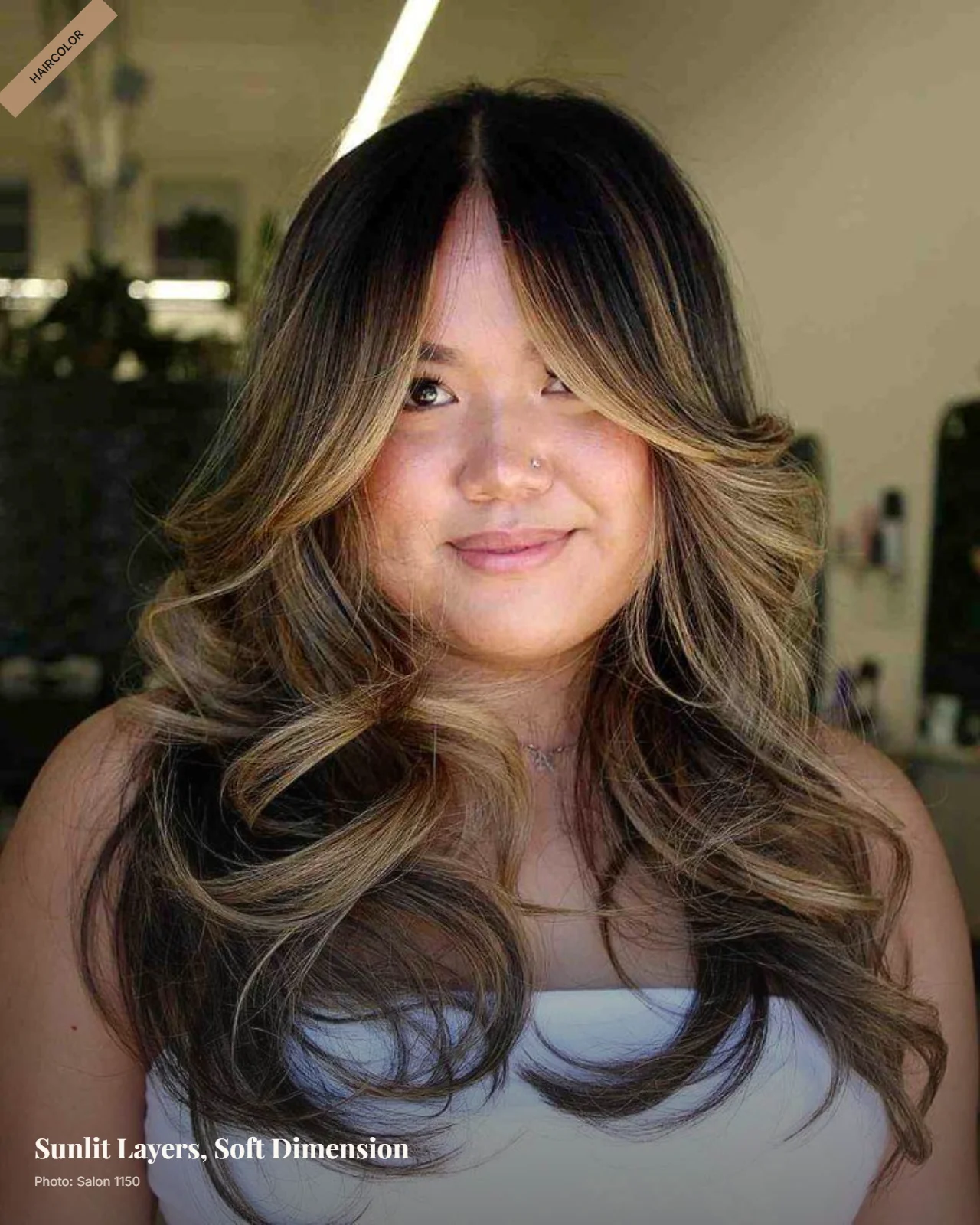 Layered wavy hair with blended balayage highlights and face-framing layers on a round face