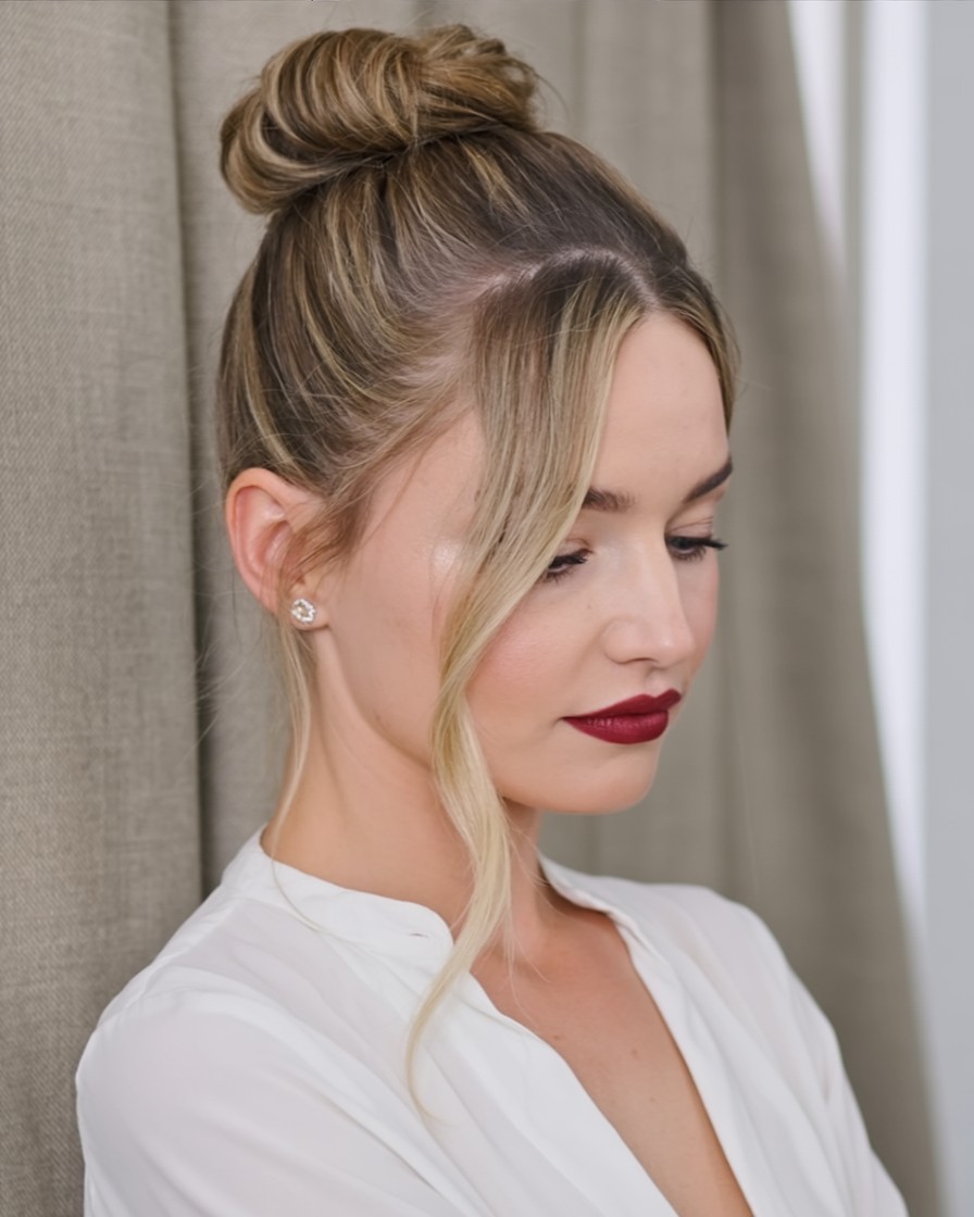 woman with high ballerina bun and soft curtain bangs, polished updo with face-framing fringe for round face shape

