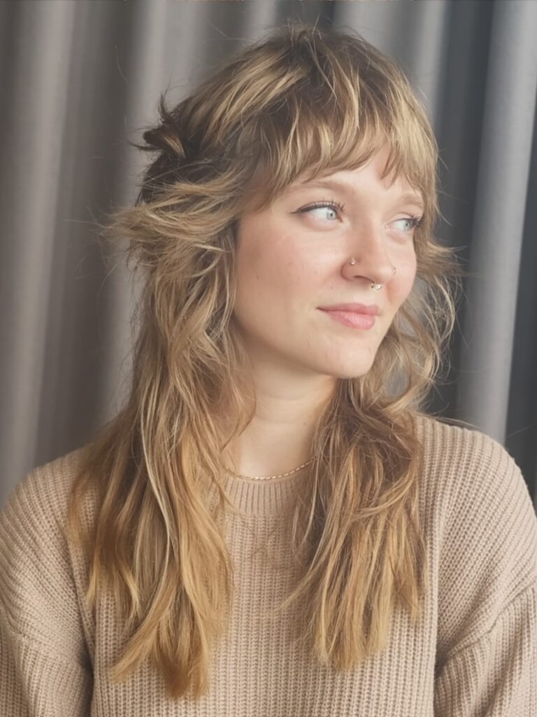 woman with long shaggy layered haircut, tousled texture styled to flatter round face shape

