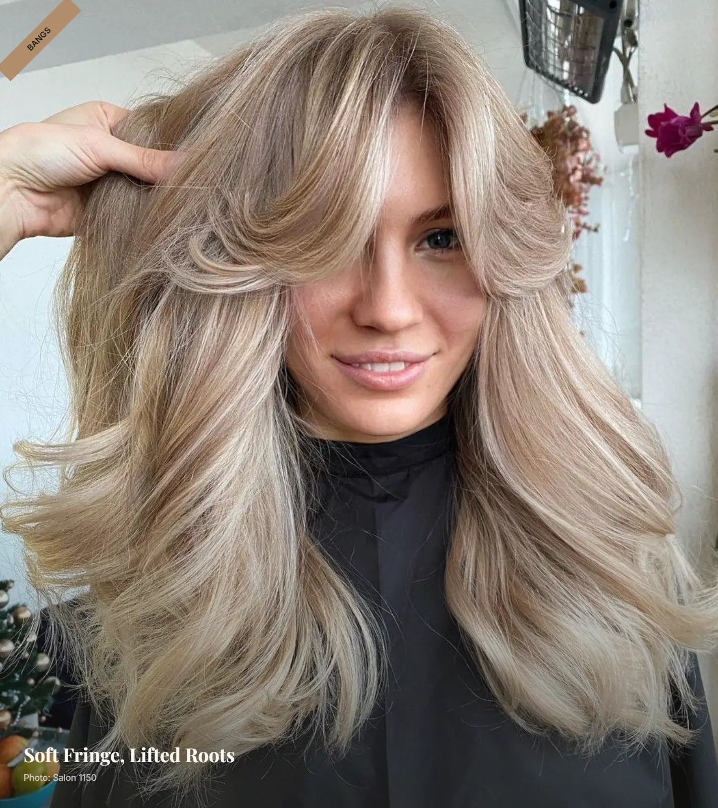 Soft curtain bangs with lifted teased roots and feathered layers framing a round face