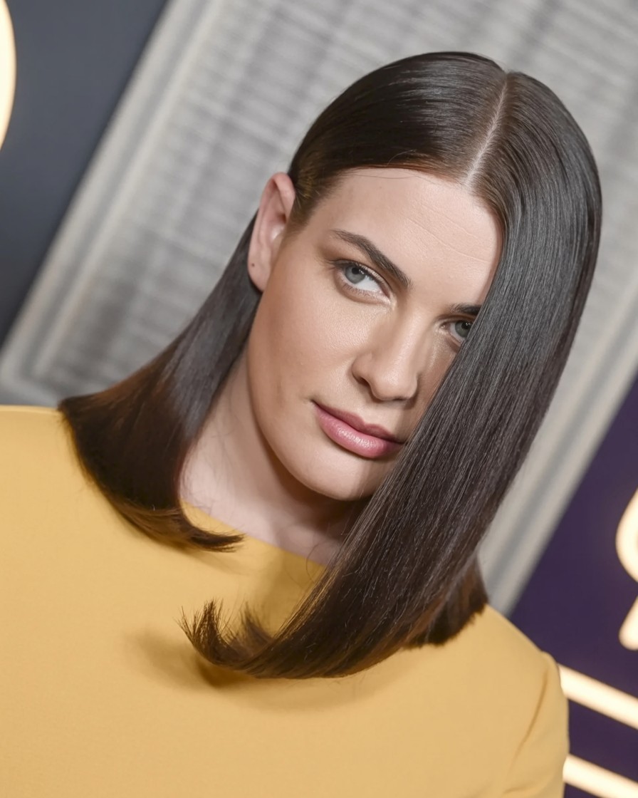 woman with sleek straight hair and deep lifted side part, styled to elongate and flatter a round face