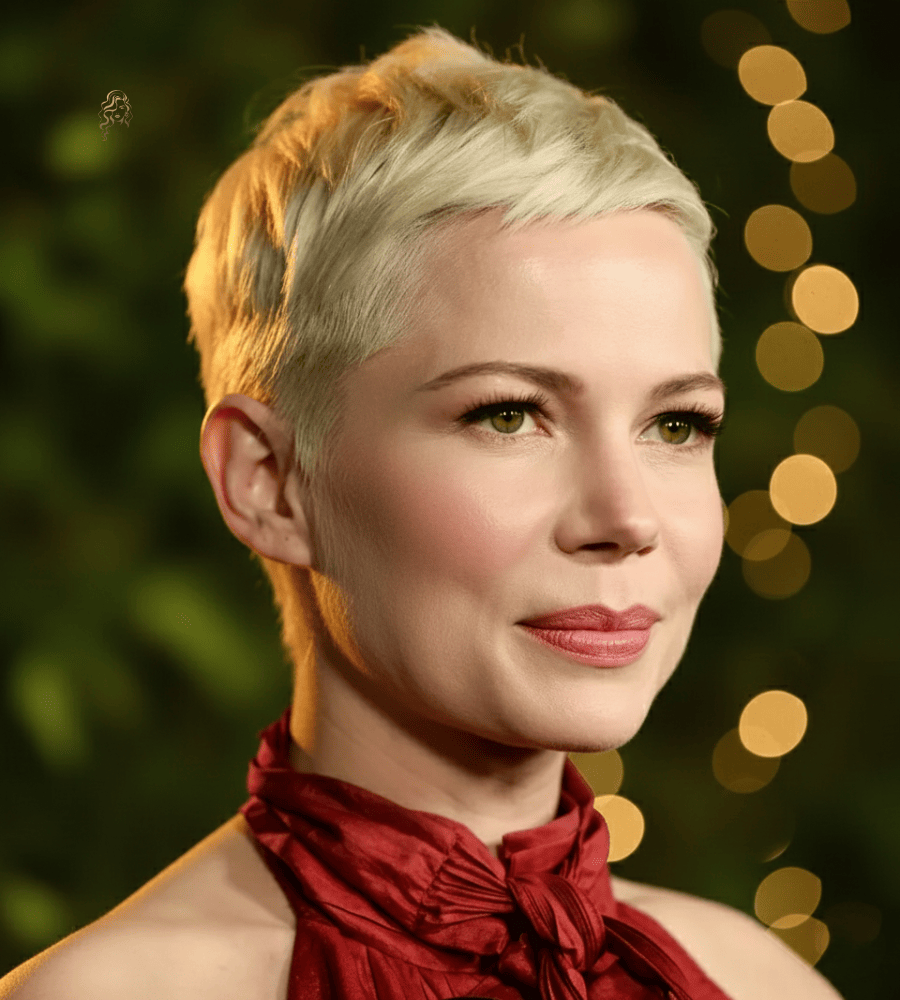 Michelle Williams with a platinum pixie cut featuring close sides, soft top texture, and cool blonde tone for a modern finish.
