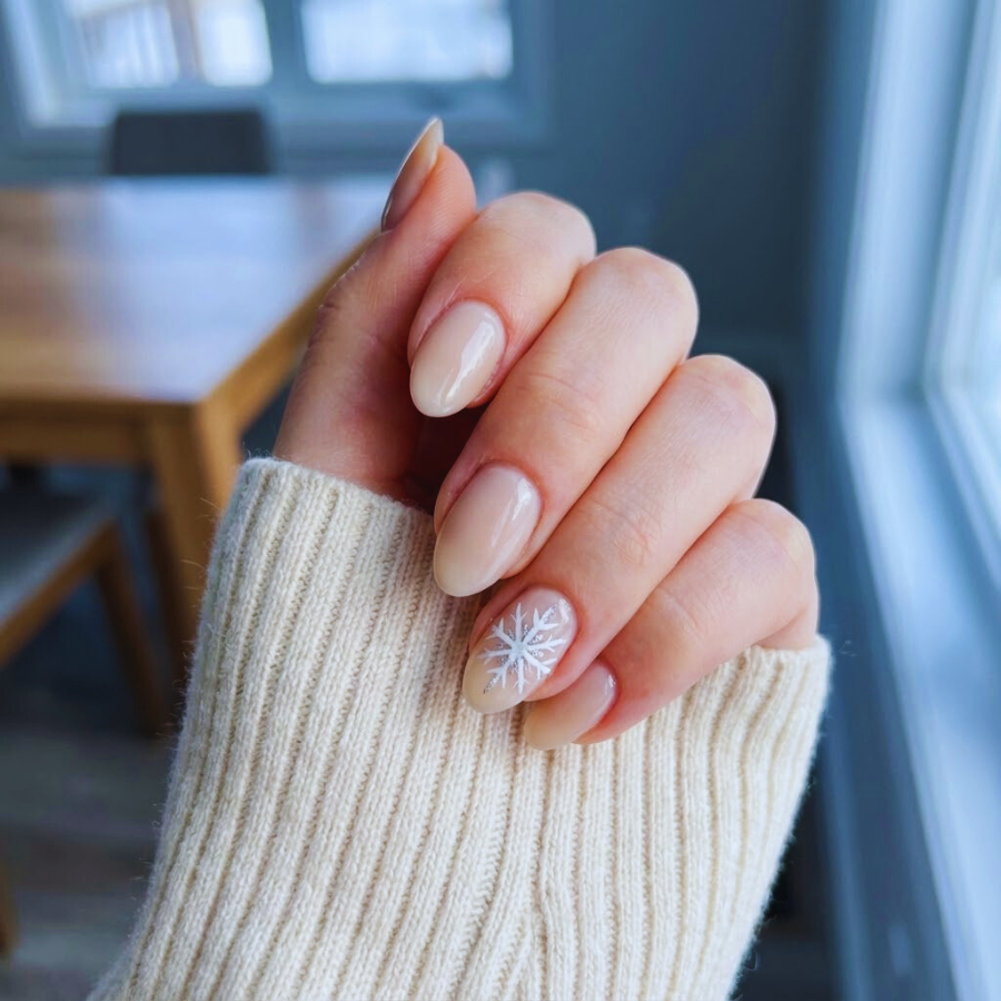 Snowflake winter Christmas nail with a soft nude base and delicate white snowflake design