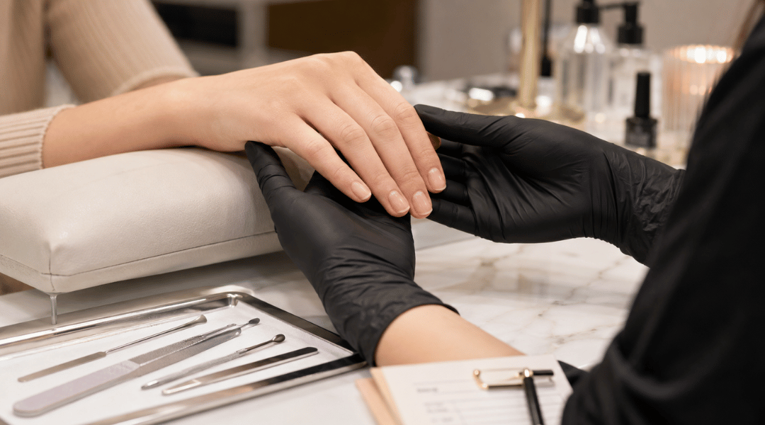 Professional nail technician examining nail health before acrylic application, checking cuticles, nail thickness, nail bed condition, and signs of damage on healthy natural nails.