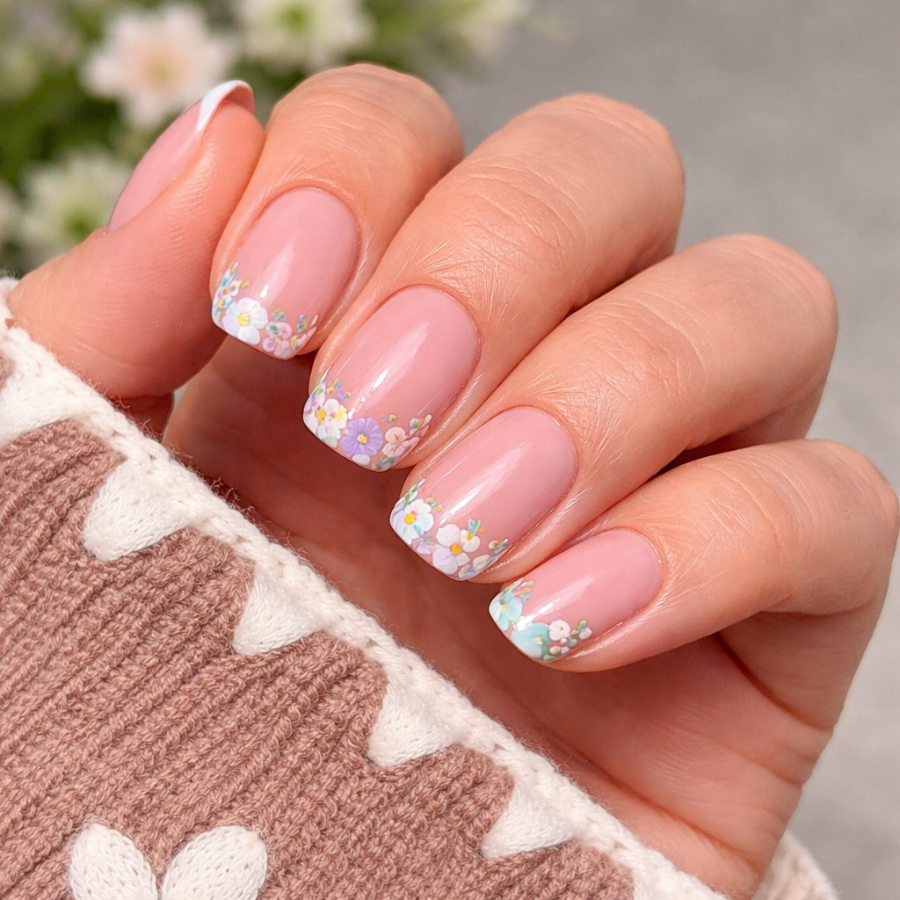 Floral french tip nails with small pastel flowers on a soft pink nude base in a spring manicure style