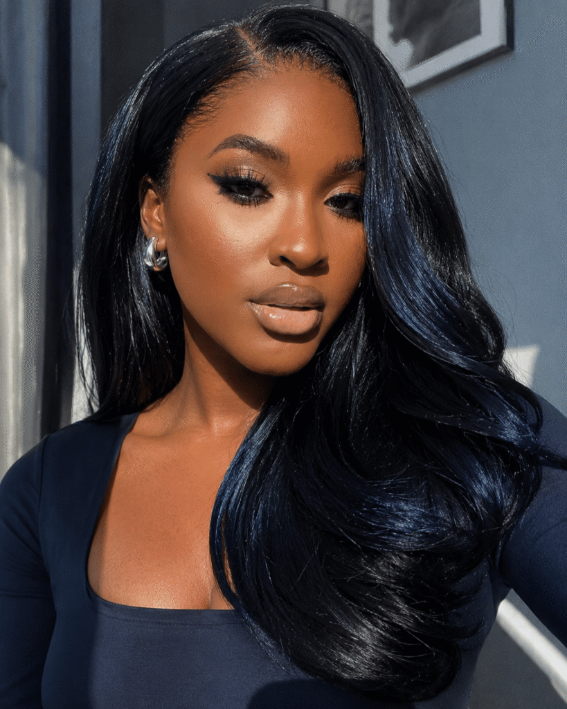 Blue-black hair color on dark skin with sleek styling and subtle cool-toned blue sheen