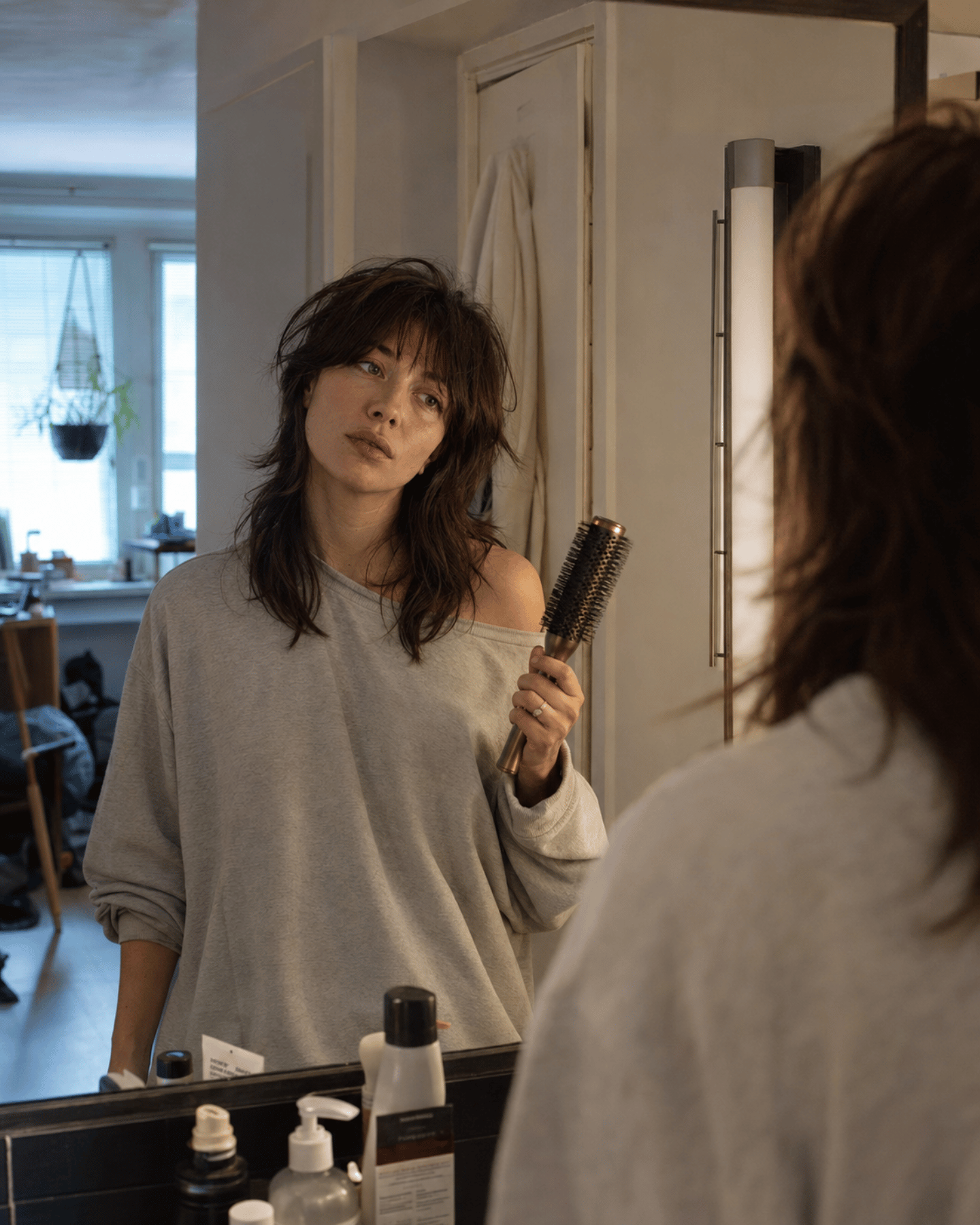 Woman with edgy layered haircut in realistic morning setting showing the difference between social media hair styling and real-life texture