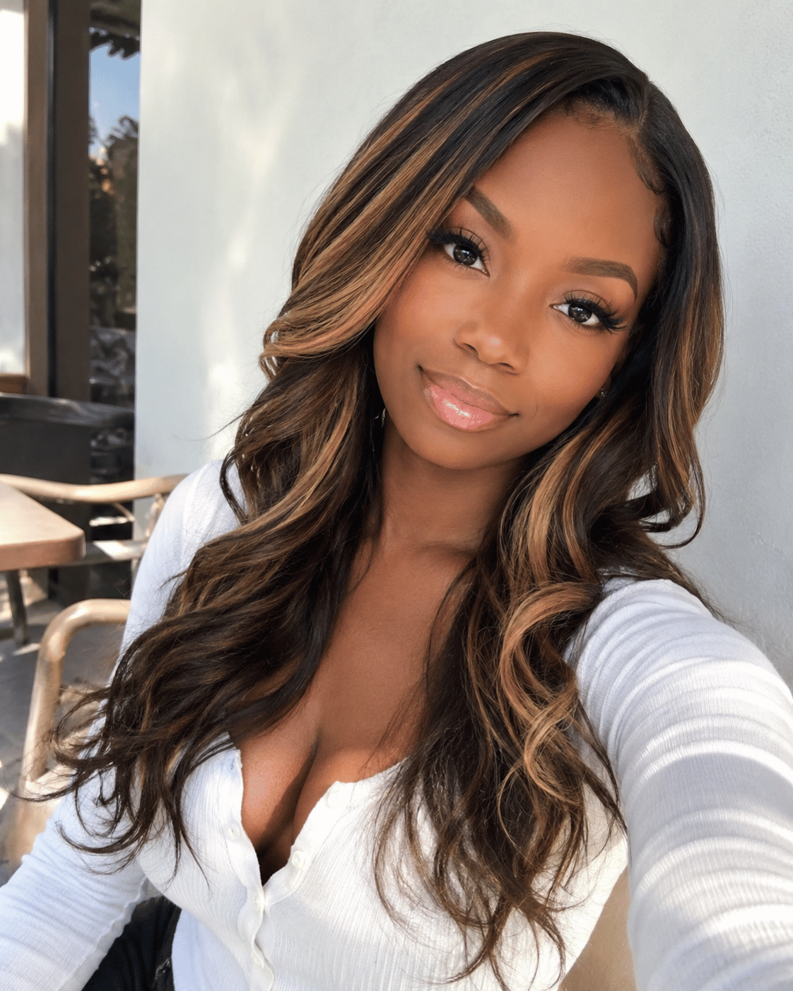 Honey blonde highlights on dark brown skin with soft curly hair and natural face-framing dimension