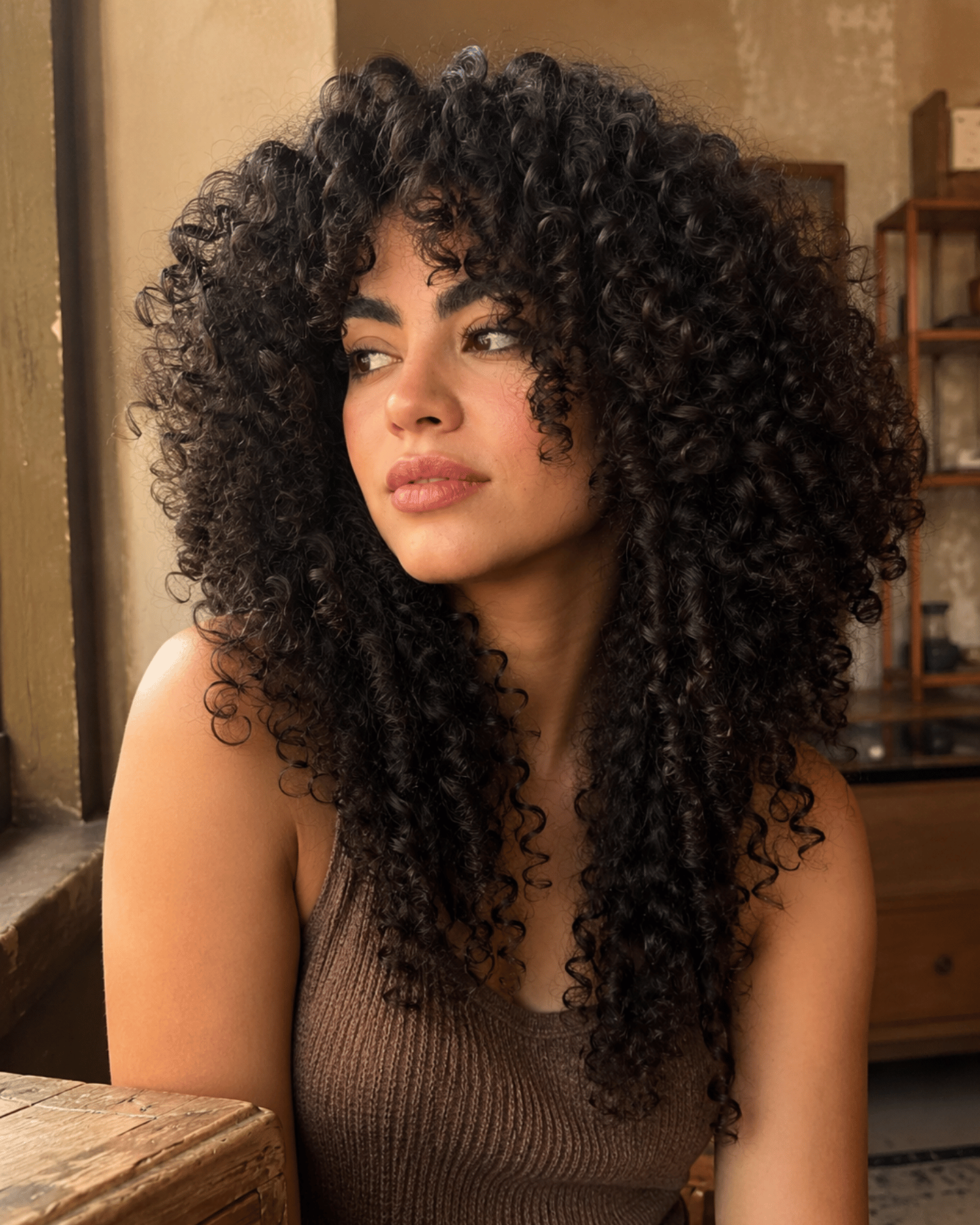 Jellyfish cut on curly hair showing dramatic rounded upper curl volume with disconnected lower curls and bold layered silhouette