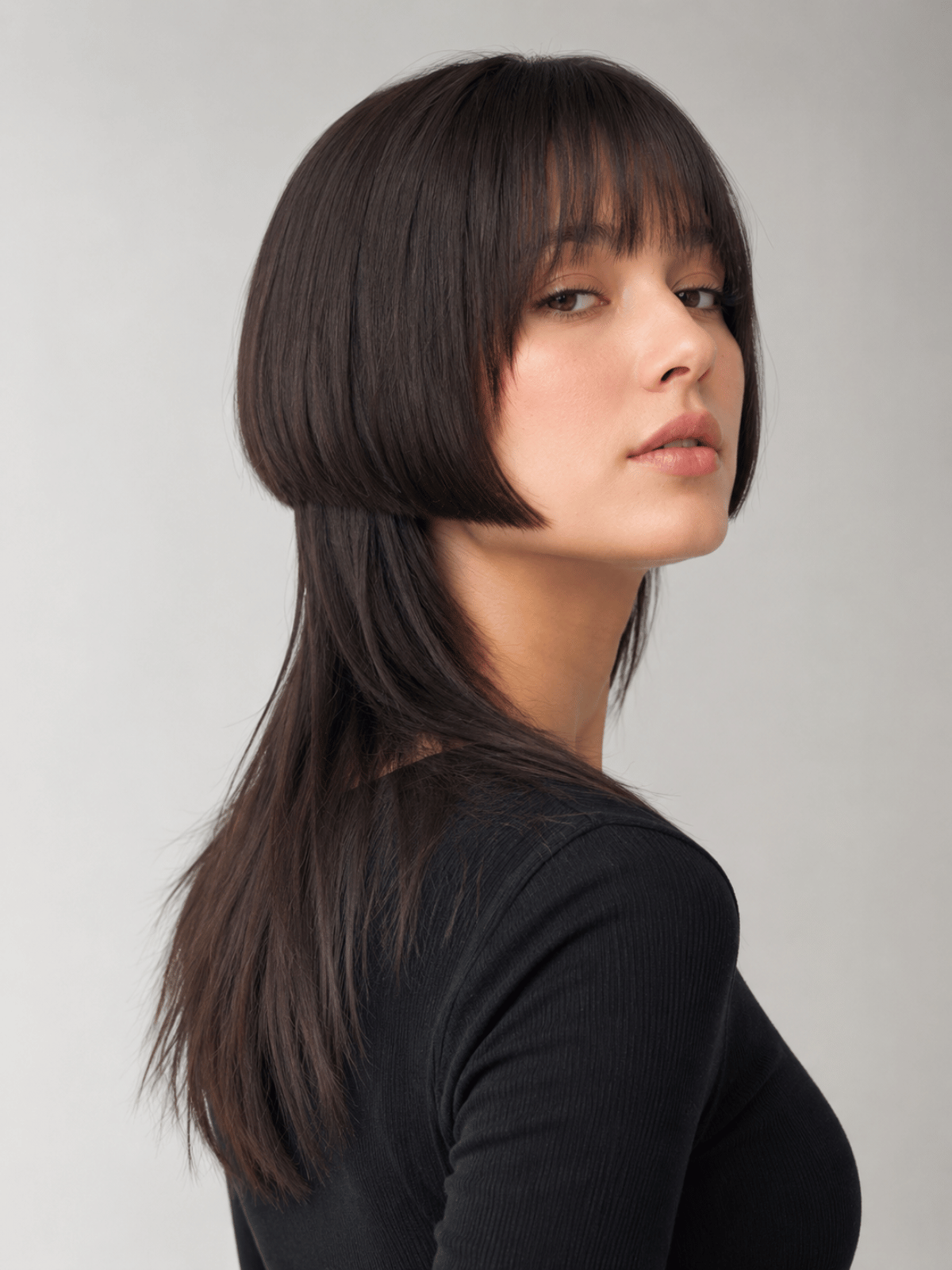 Woman with a sharp jellyfish haircut featuring disconnected chin-length layers and long straight bottom layers styled in a polished editorial look.