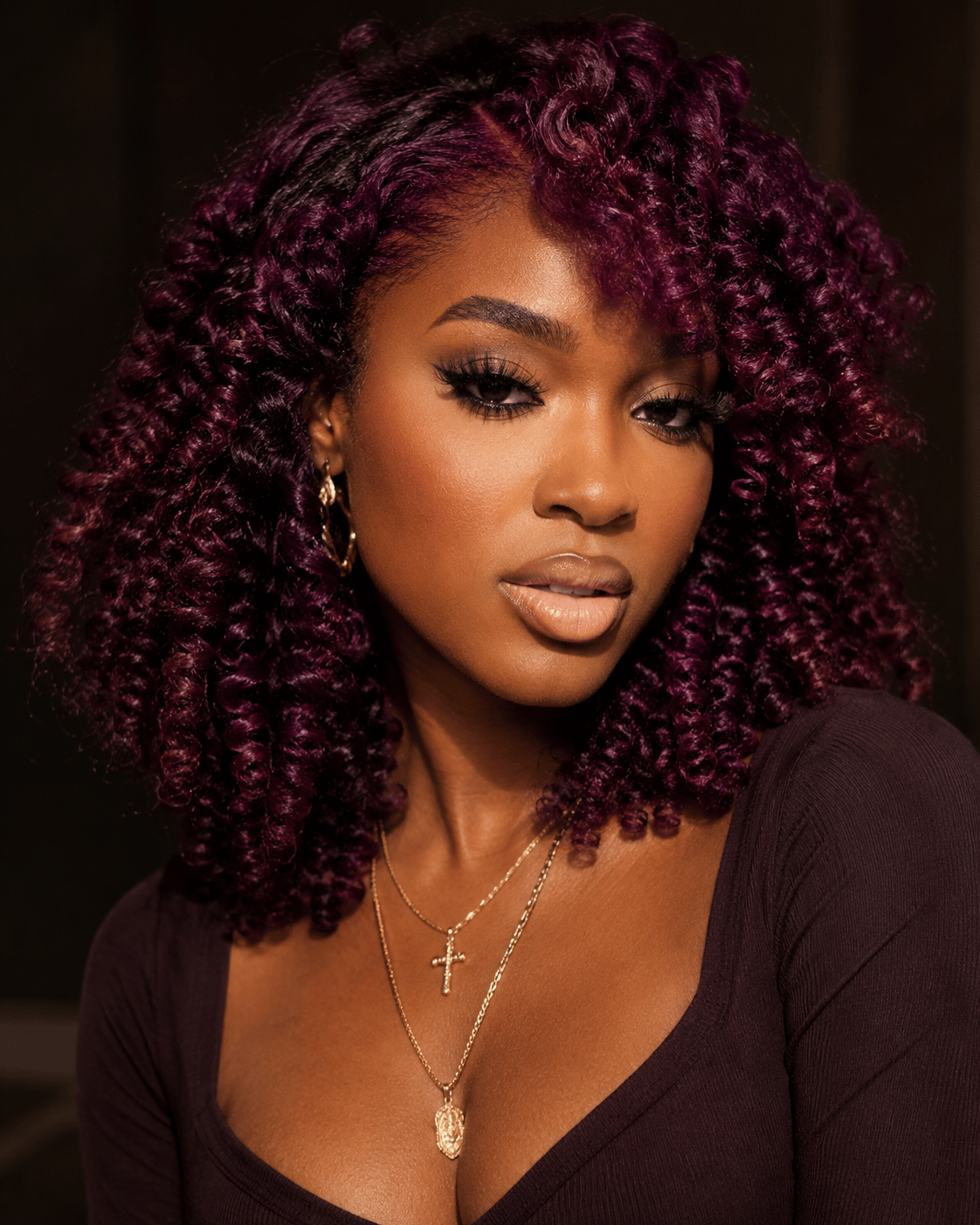 Plum hair color on dark skin with defined natural curls and rich jewel-toned dimension