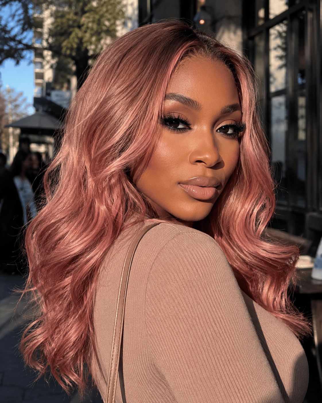 Rose gold hair color on dark brown skin with soft metallic pink-copper waves in natural outdoor lighting