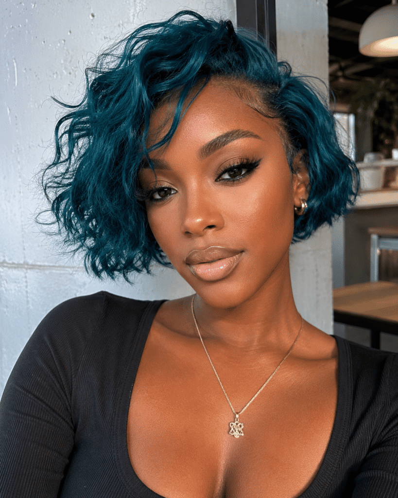 Teal hair color on deep dark skin with short textured styling and vivid blue-green contrast