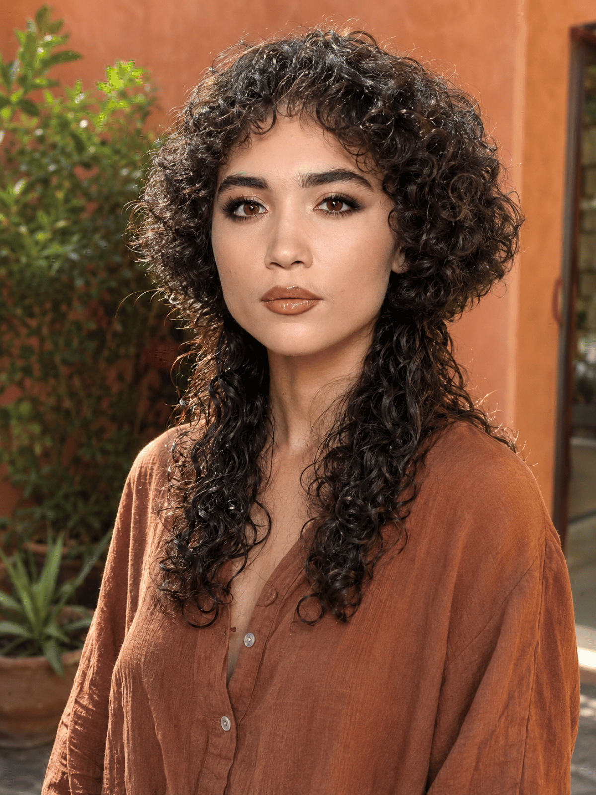 Jellyfish haircut on curly hair featuring a rounded voluminous top layer and longer curly bottom section with natural texture.