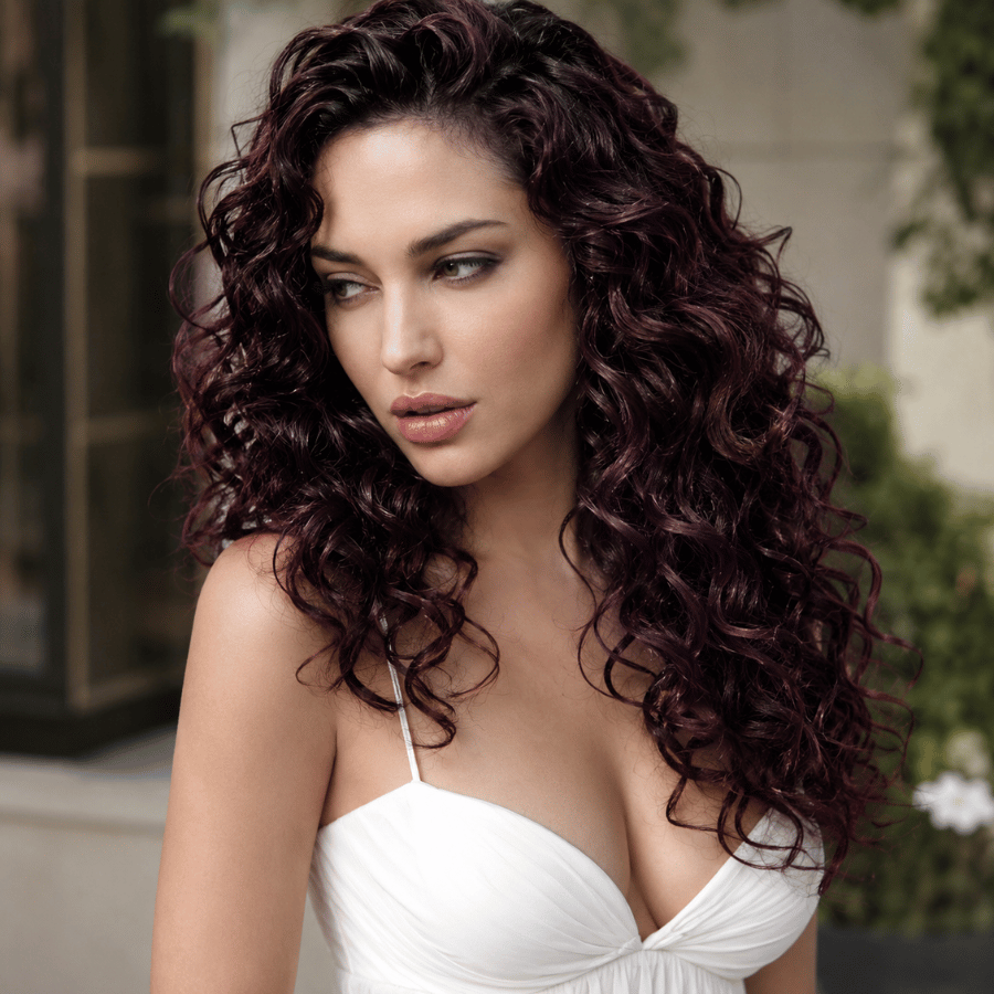 Woman with black cherry plum hair color on natural curly hair featuring rich burgundy-plum dimension and glossy curls.