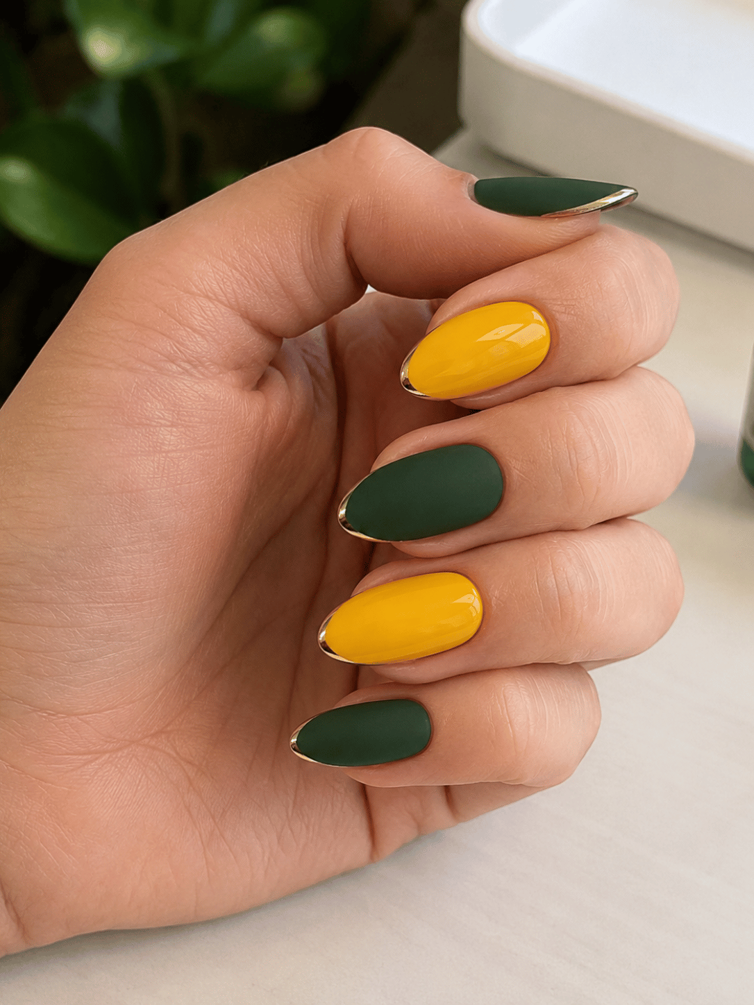 Brazil almond nails with matte green nails glossy yellow nails and gold chrome tip detail