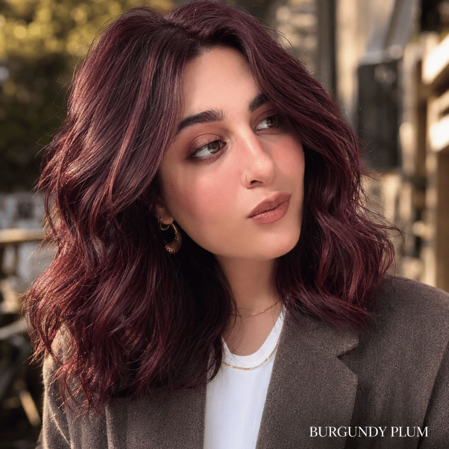 Woman with burgundy plum hair color featuring rich wine-red and soft purple undertones on long layered hair.