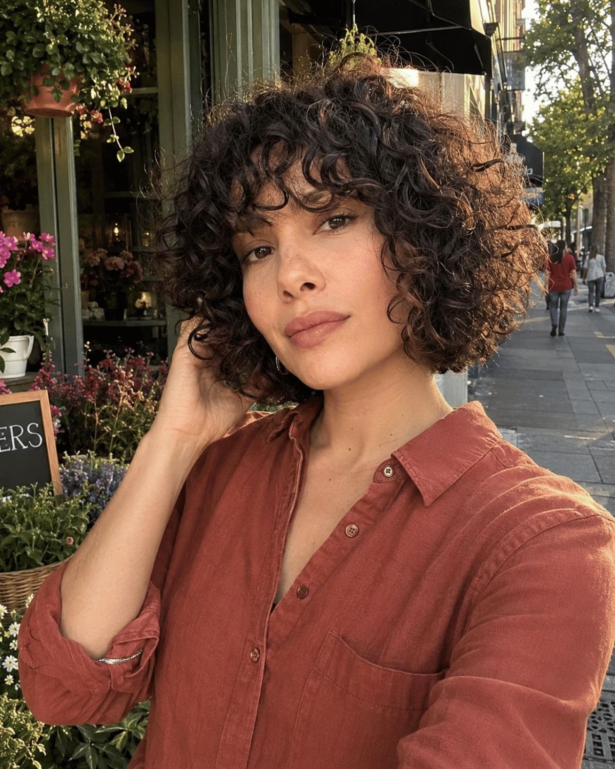 Woman wearing a curly French bob haircut with 3A–3B curls, natural volume, and a rounded chin-length shape.