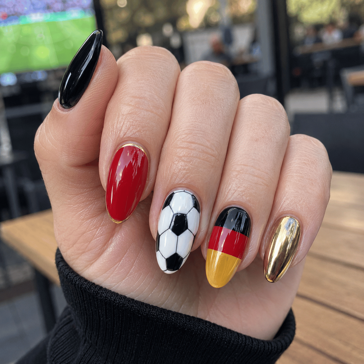 Germany football supporter nails featuring black red and gold accent nail art with soccer ball details and glossy almond manicure.