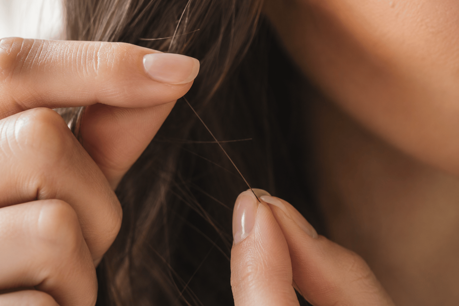 Fingers performing a strand slide test to assess hair cuticle texture and porosity