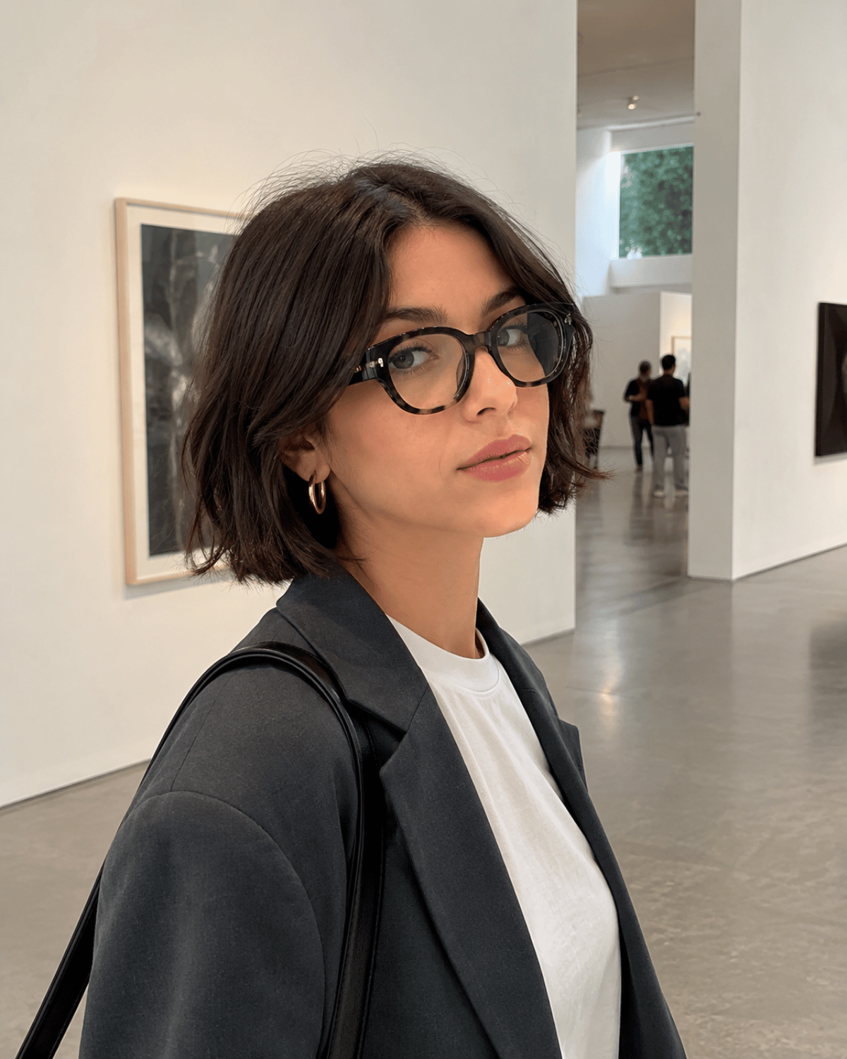 Woman wearing a modern French bob haircut without bangs featuring a center part, chin-length shape, and clean jawline framing.