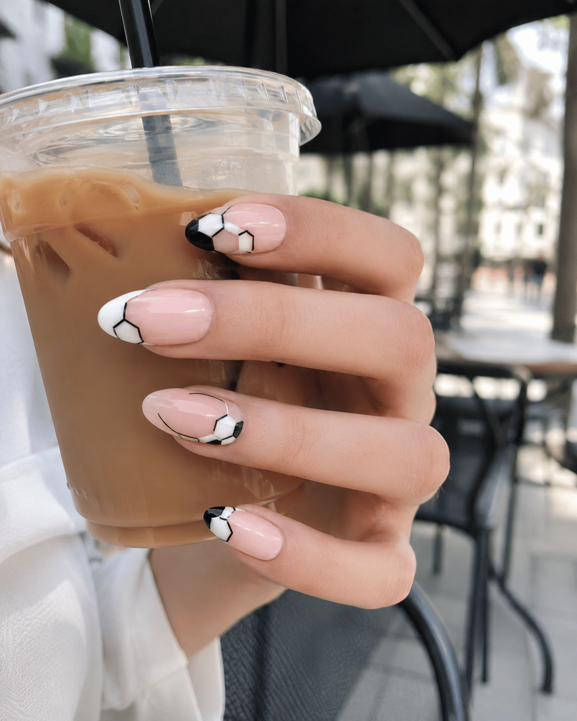 Modern soccer ball nails featuring minimalist black and white football-inspired nail art with negative space details.