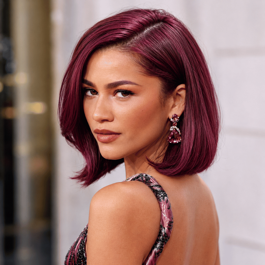 Woman with vivid raspberry plum hair color on a sleek bob haircut featuring bright berry and violet tones with dimensional shine.