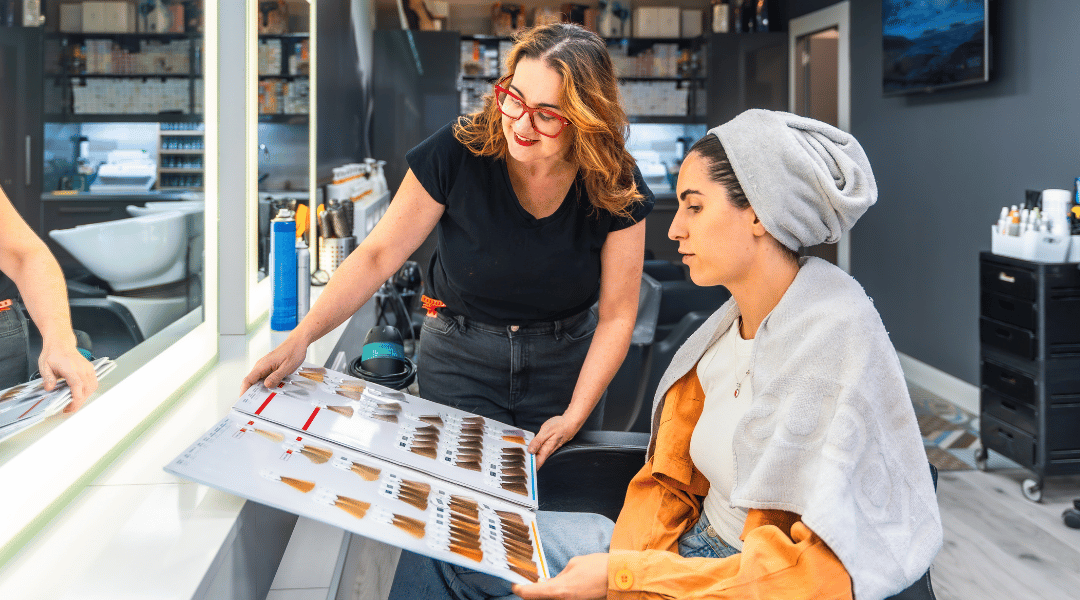 Cosmetologist discussing hair color options with a client using a color chart