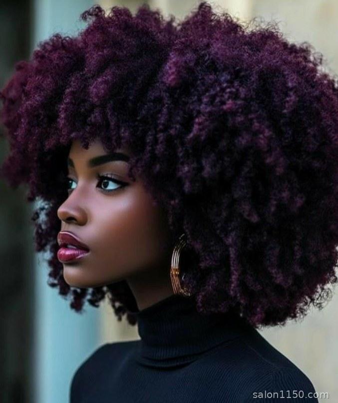 Velvet burgundy hair color on a woman with deep skin tone and natural curly hair