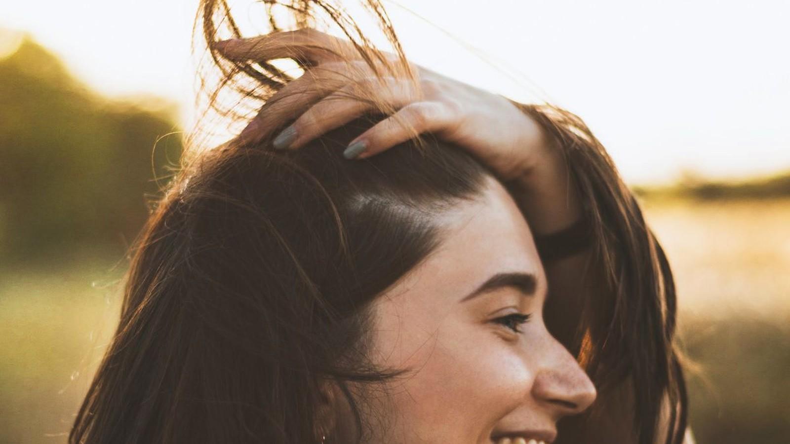 Laughing woman with fresh vibrant hair color in golden sunlight
