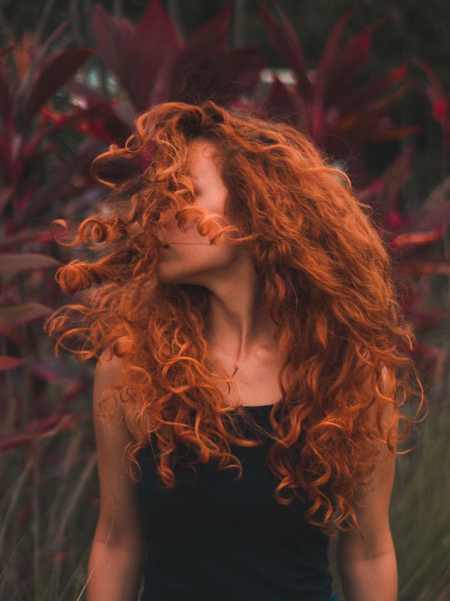 Woman with vibrant copper-red curly hair after a virtual hair color try-on