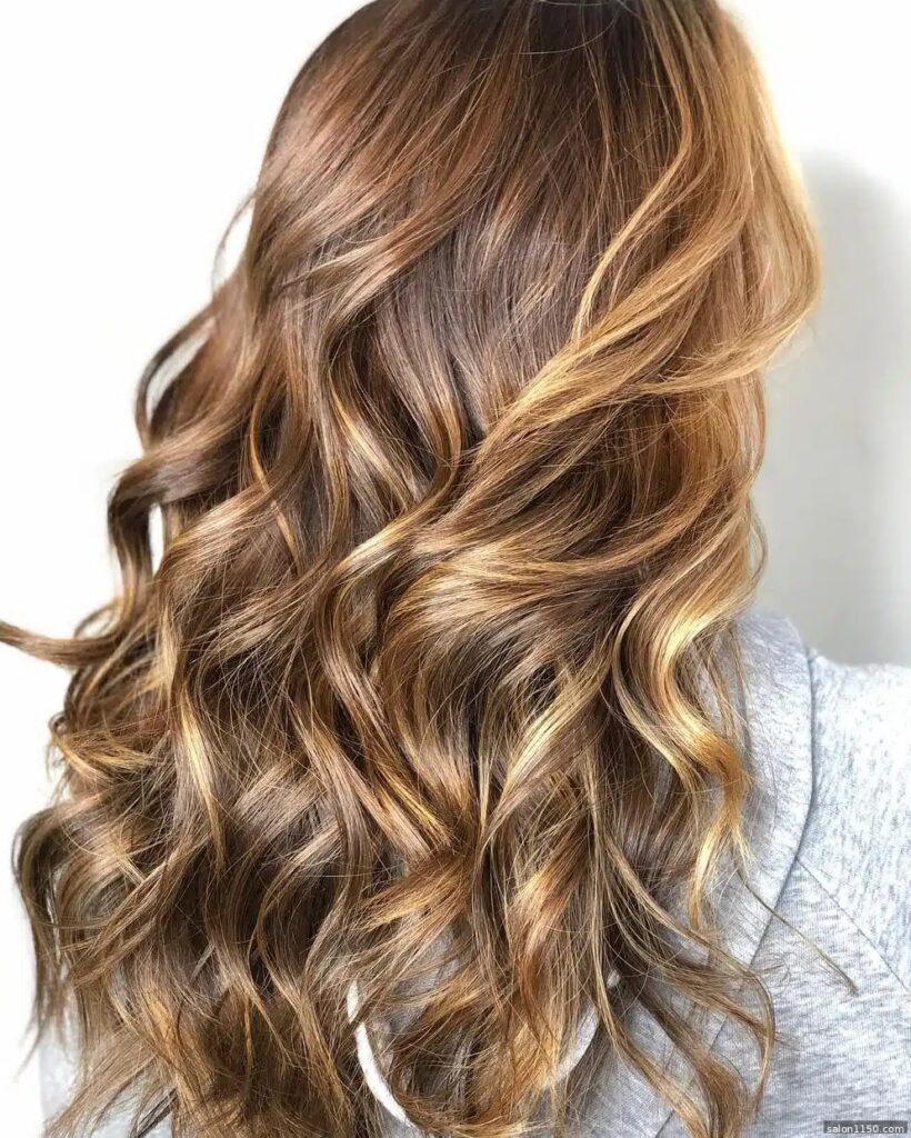 Honey bronde hair color with warm golden tones on wavy hair