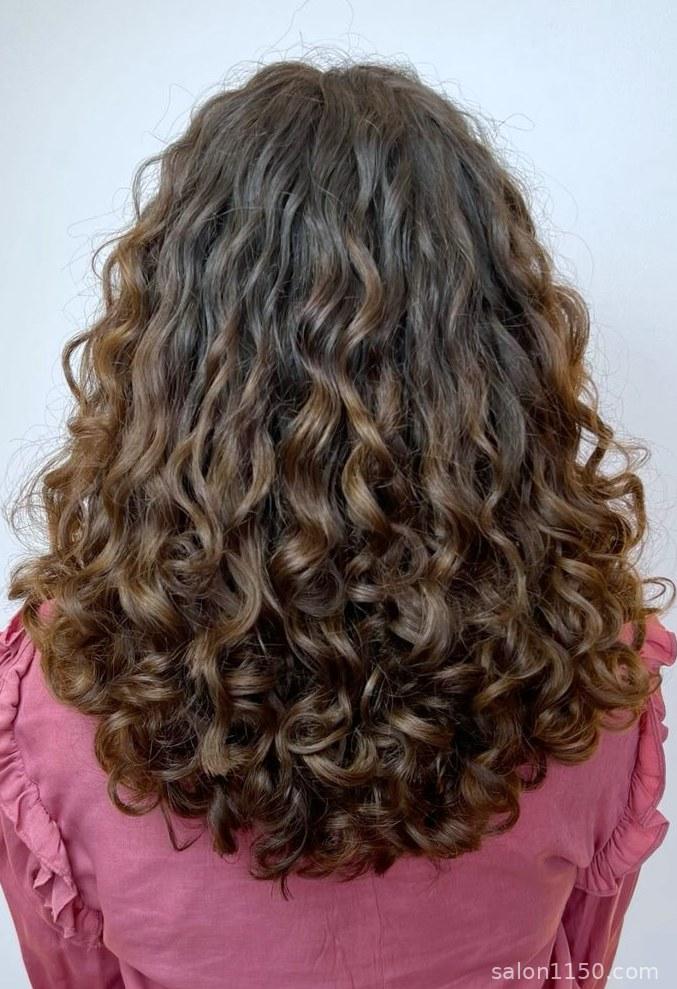Mushroom brown hair color on natural curly hair showing dimensional cool tones