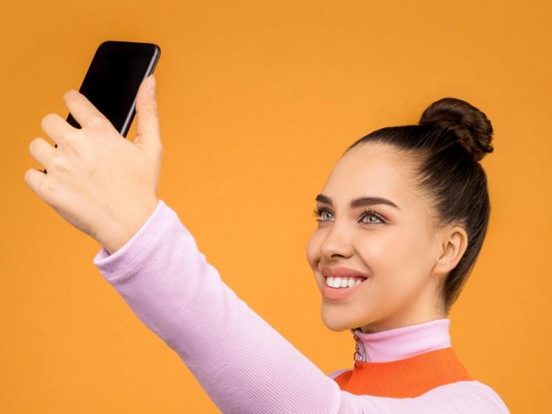 Woman taking a selfie in daylight with her smartphone